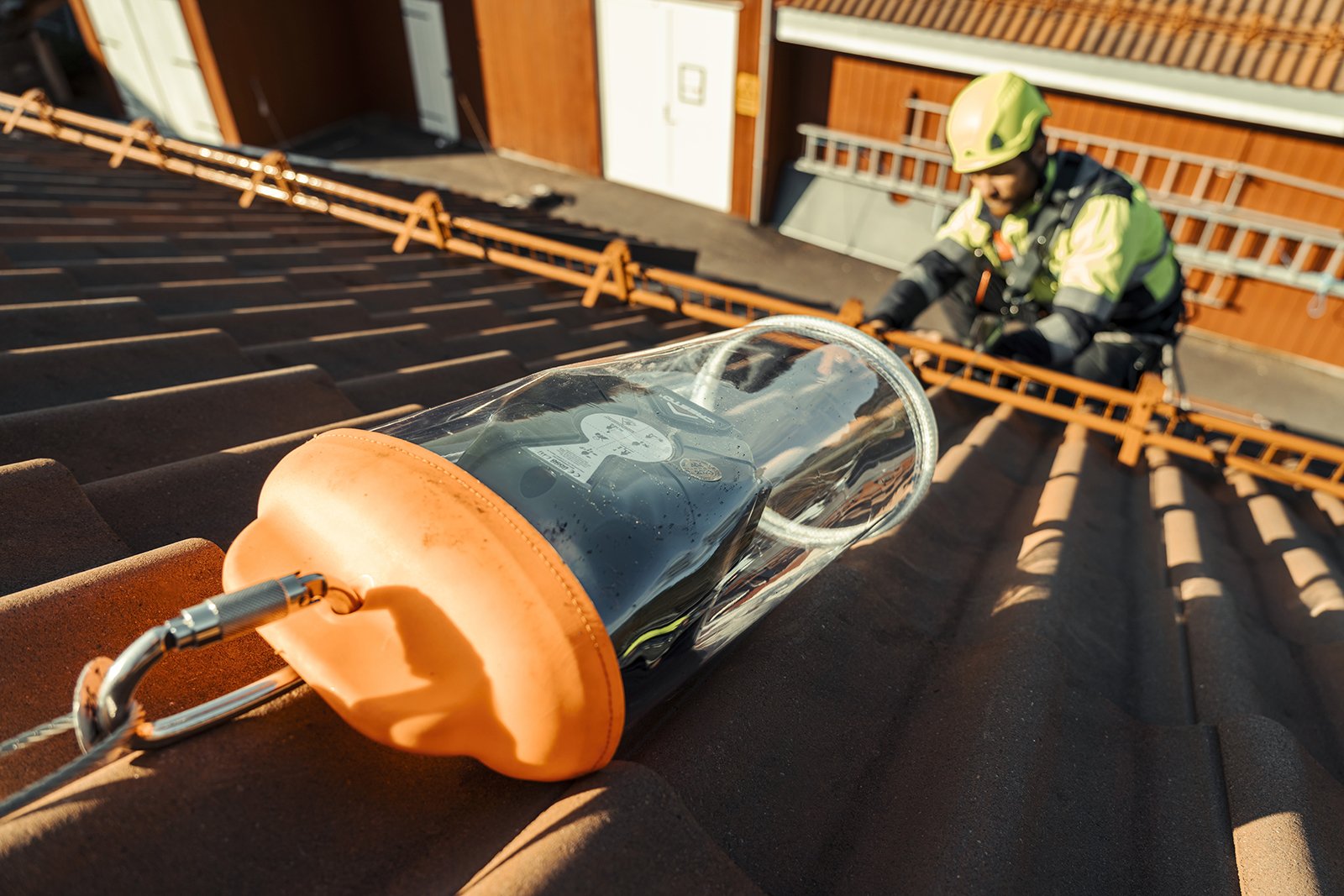 Mann som jobber på tak med fallblokk i et fast system og personlig verneutstyr. 