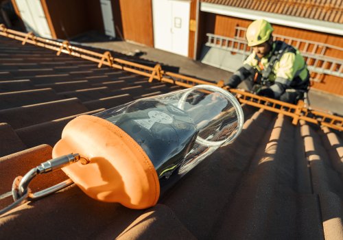 Mann som jobber på tak med fallblokk i et fast system og personlig verneutstyr. 