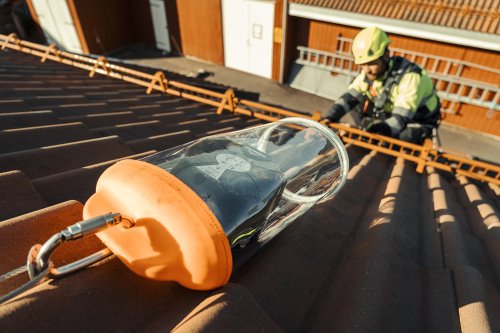 Mann som jobber på tak med fallblokk i et fast system og personlig verneutstyr. 